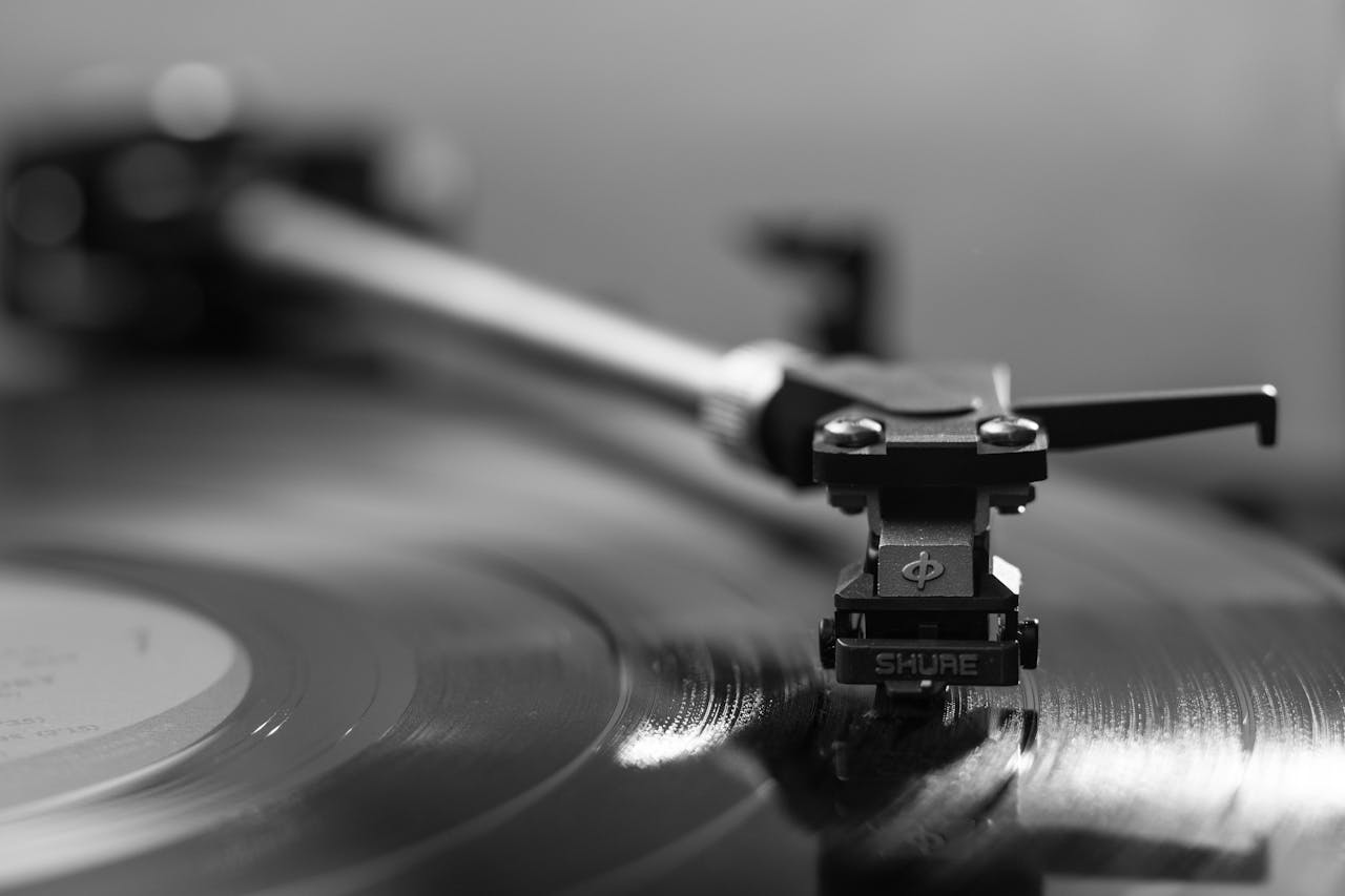Black and white close-up of a turntable playing a vinyl record, emphasizing vintage aesthetics.